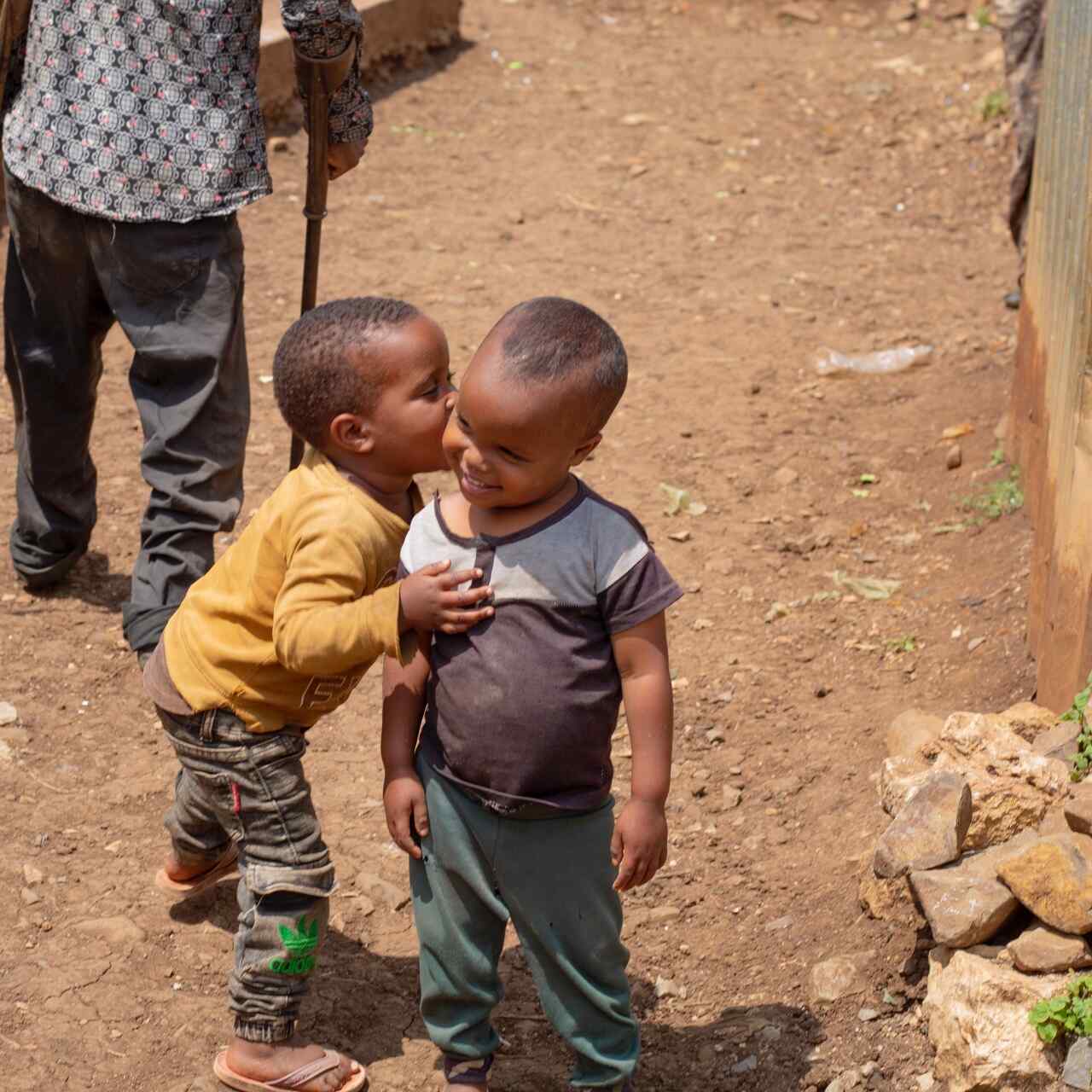 Two young children in Ethiopia embrace outside. They smile together.